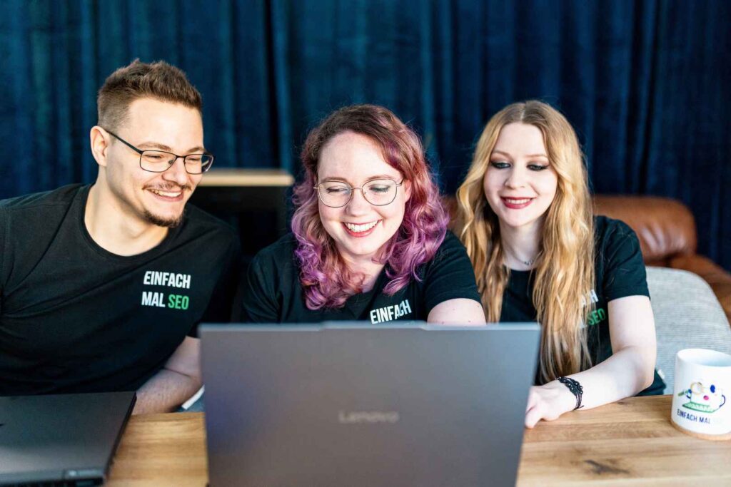 Teammitglieder von Einfach mal SEO arbeiten gemeinsam an einem Laptop.